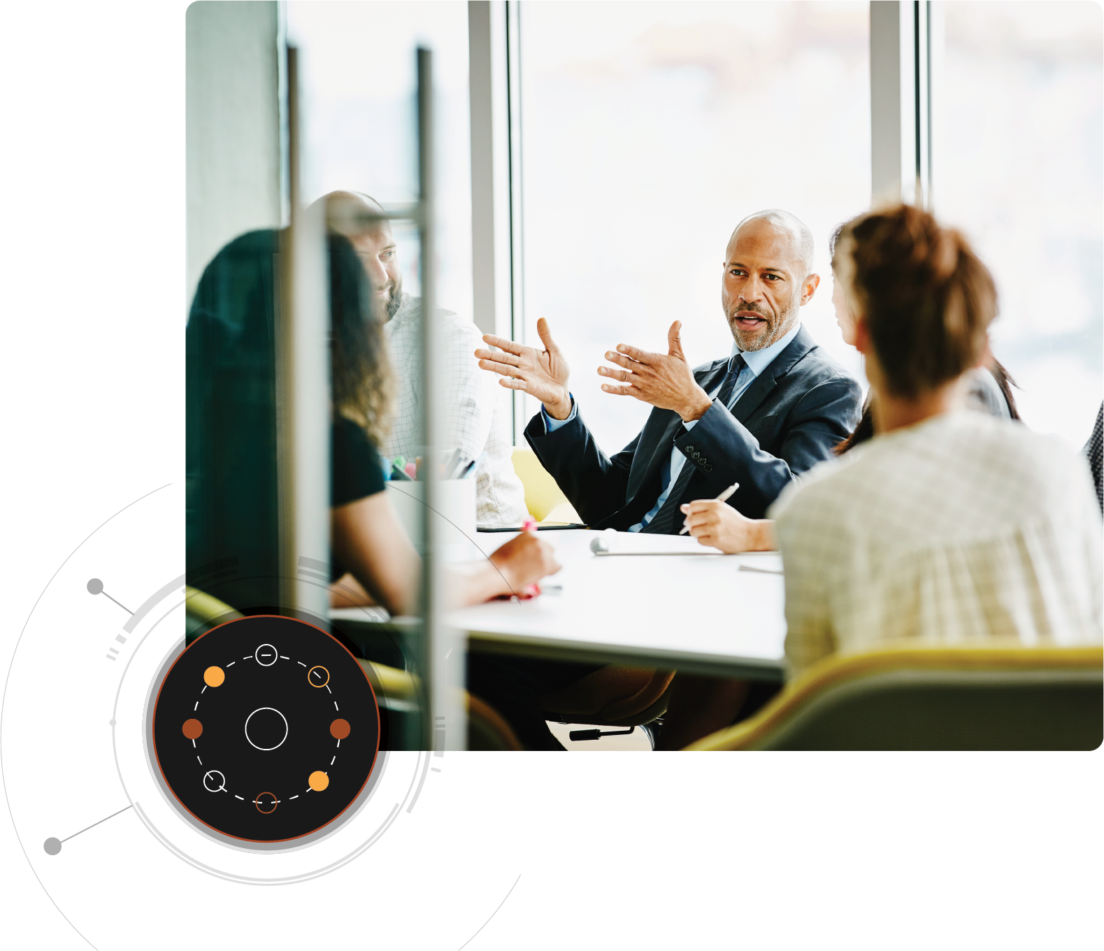 Un homme parle à plusieurs personnes assises autour d’une table de conférence ; un graphique circulaire apparaît au premier plan en bas à gauche.